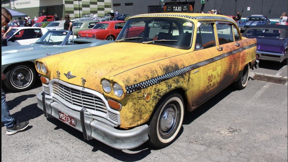 A vintage yellow Checker cab taxi at a classic car show